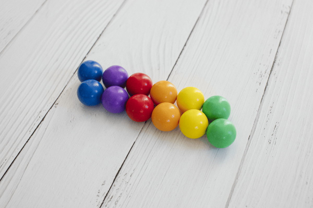 Twaalf houten CONNETIX ballen in heldere regenboogkleuren