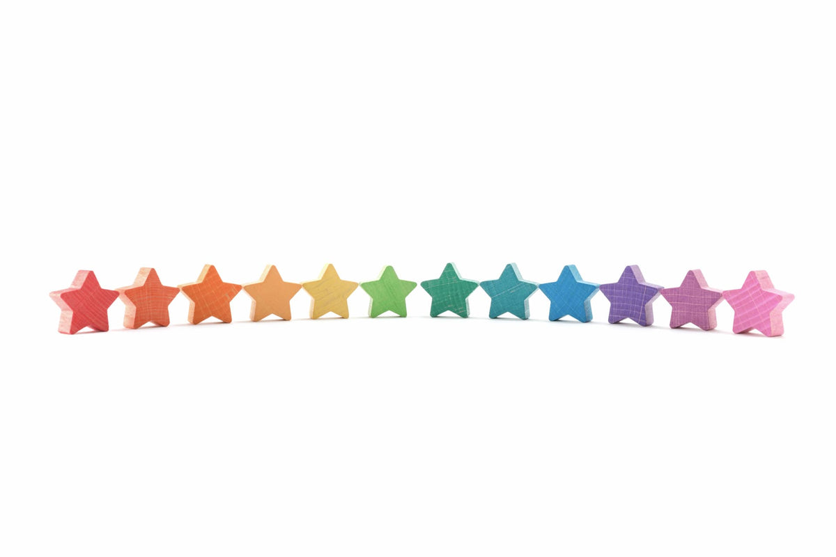 Twaalf houten sterren van Ocamora in regenboogkleuren op rij