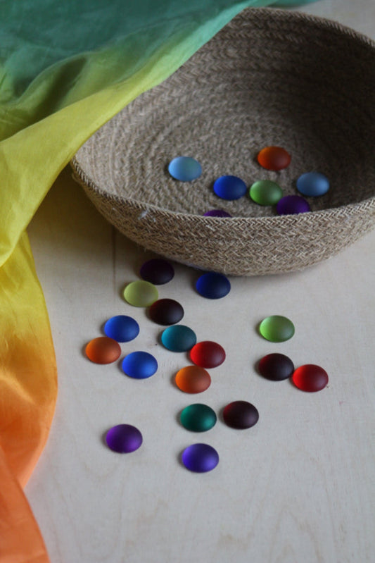 Ronde matte fonkelstenen van Bauspiel in twaalf zachte kleuren in mand en op de grond.