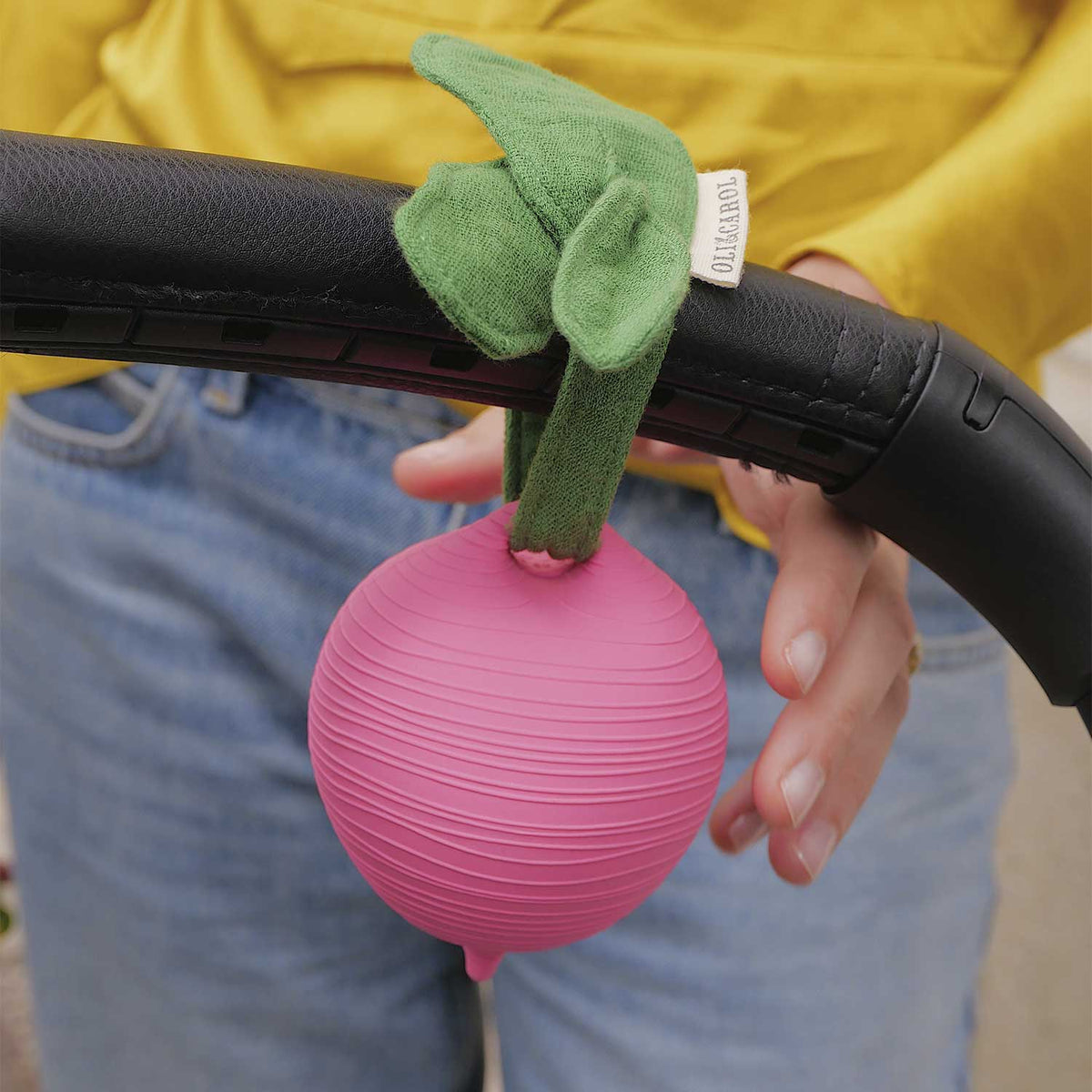 Oli&Carol speenkokertje Ramona the Radish, radijsvorm met mousseline blad aan kinderwagen