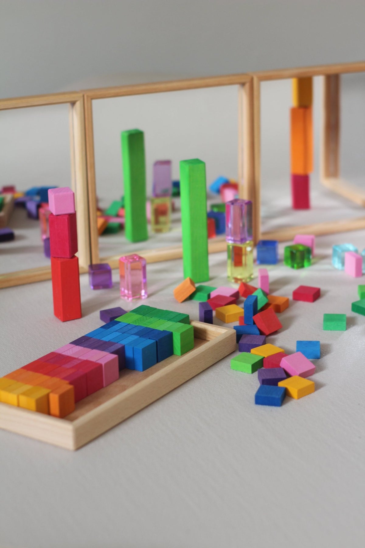 Honderd vierkante houten mozaïekstenen van Bauspiel in tien kleuren en een houten frame. Gecombineerd in fantasiespel