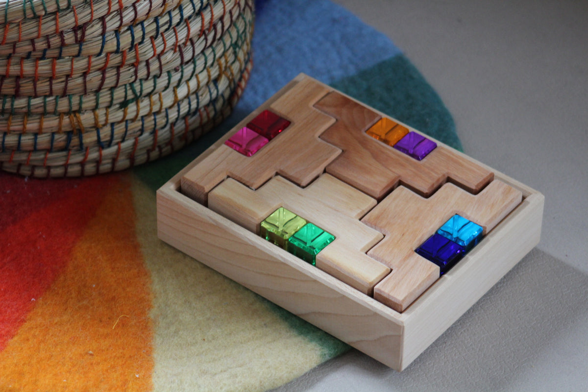Acht natuurlijke houten trapblokken en acht gekleurde lichtbouwstenen van Bauspiel in een houten frame