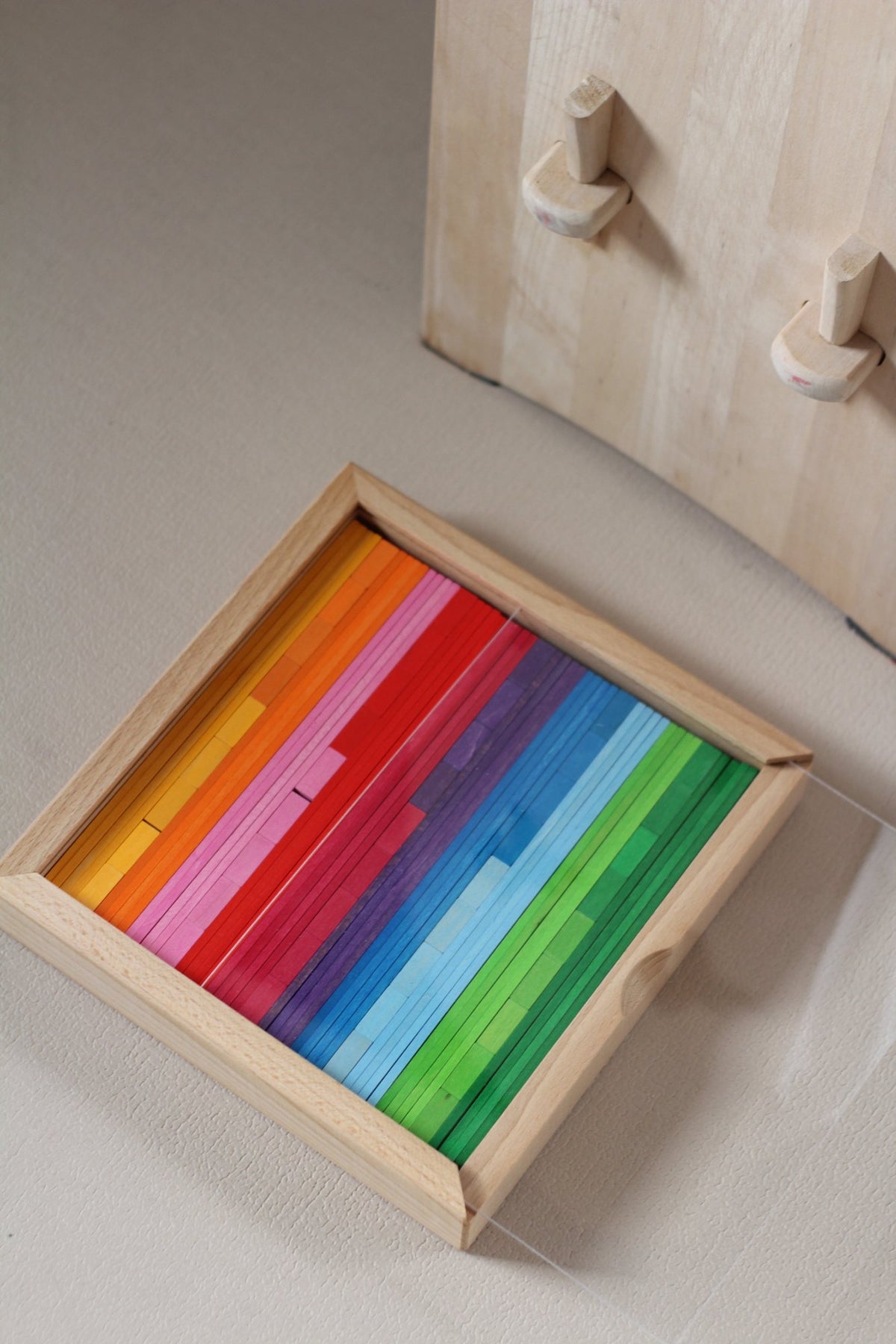 Bauspiel Kombibox K85 met gekleurde bouwplanken en mozaïekstenen in een houten kist op de grond
