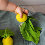 Oli&Carol mini doudou-bijtring Lou the Lemon met mousseline blad in kinderhand