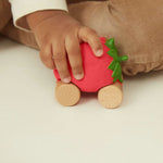 Oli&Carol speelgoedautootje Sweety the Strawberry, aardbeivorm op houten wieltjes in kinderhand