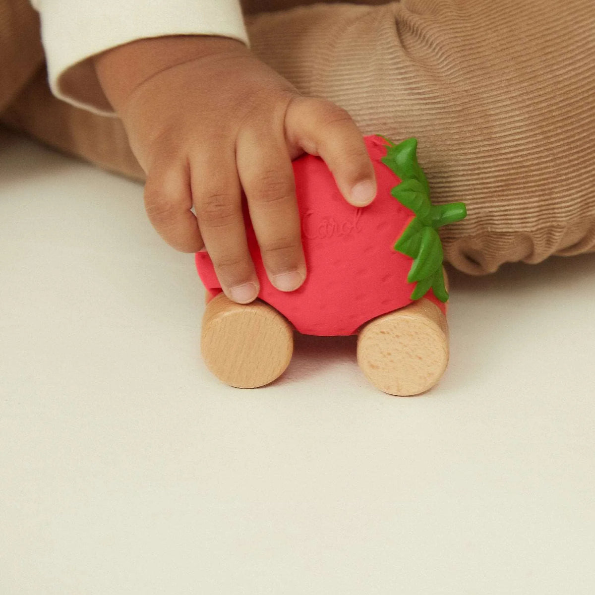 Oli&Carol speelgoedautootje Sweety the Strawberry, aardbeivorm op houten wieltjes in kinderhand