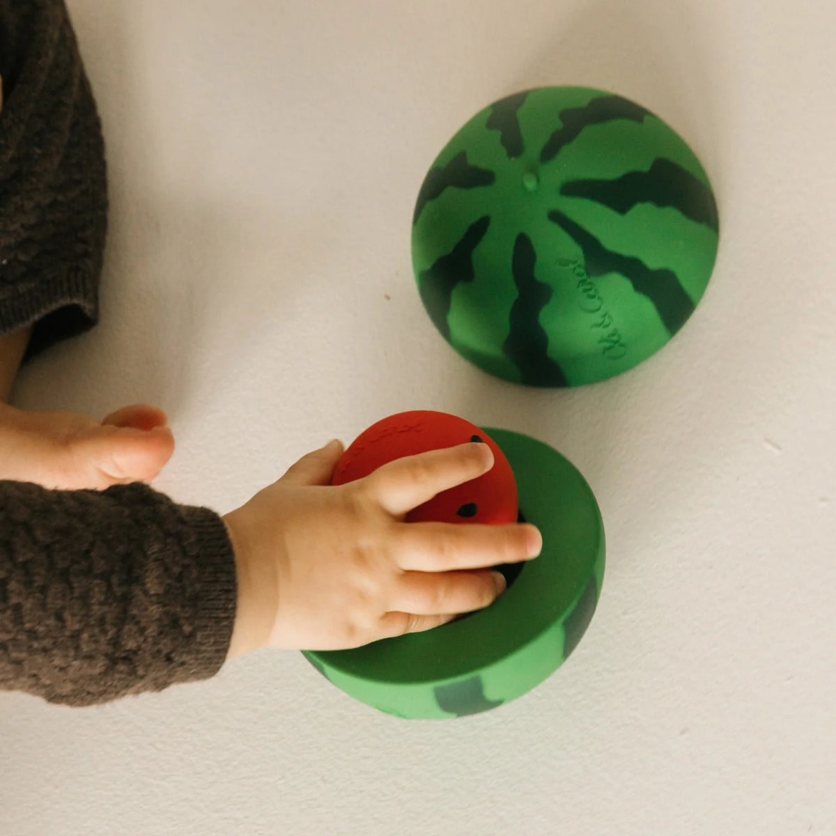 Oli&Carol Stack&Bounce Watermelon, watermeloenvormig stapel- en rammelspeeltje. Kind speelt ermee