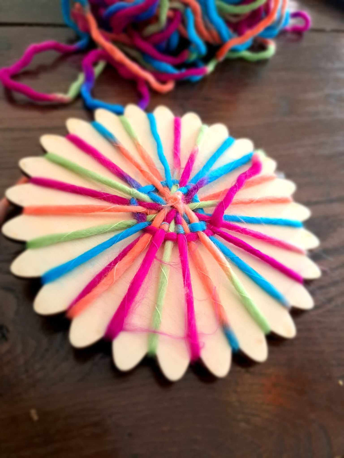 Houten weefwondertje met regenboogkleurig garen half geweven